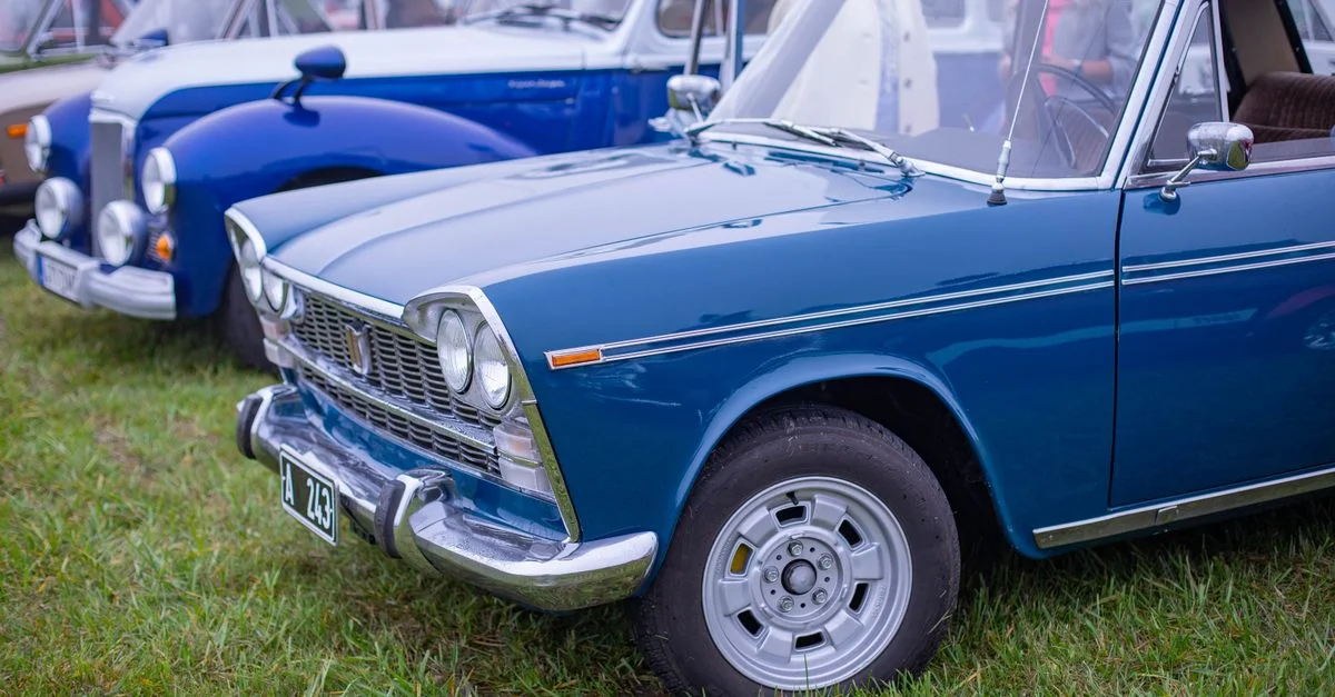 Des voitures classiques bleues vintage garées sur un champ gazonné, mettant en valeur le design automobile rétro.