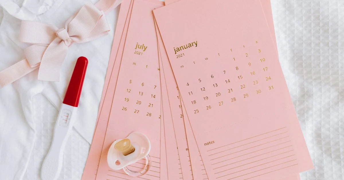 Vue de dessus d'un test de grossesse, de cartes de calendrier et d'articles pour bébé symbolisant de nouveaux départs.