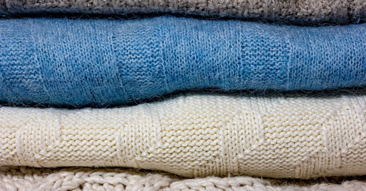 Un gros plan de divers tissus en laine tricotés colorés empilés ensemble.