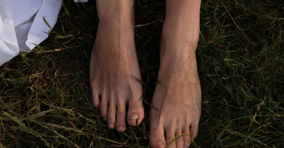 Gros plan sur les pieds nus d'une femme dans l'herbe, transmettant une ambiance estivale naturelle et sereine.