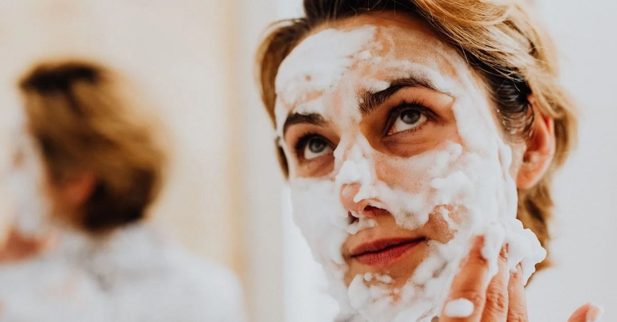 Gros plan sur une femme appliquant un nettoyant moussant pour une routine de soin rafraîchissante.