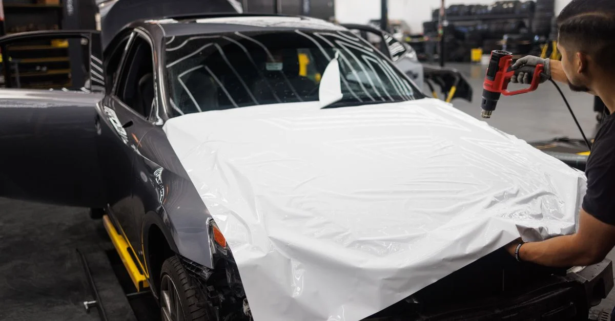 Voiture enroulée avec du vinyle blanc dans un atelier automobile par un mécanicien qualifié.