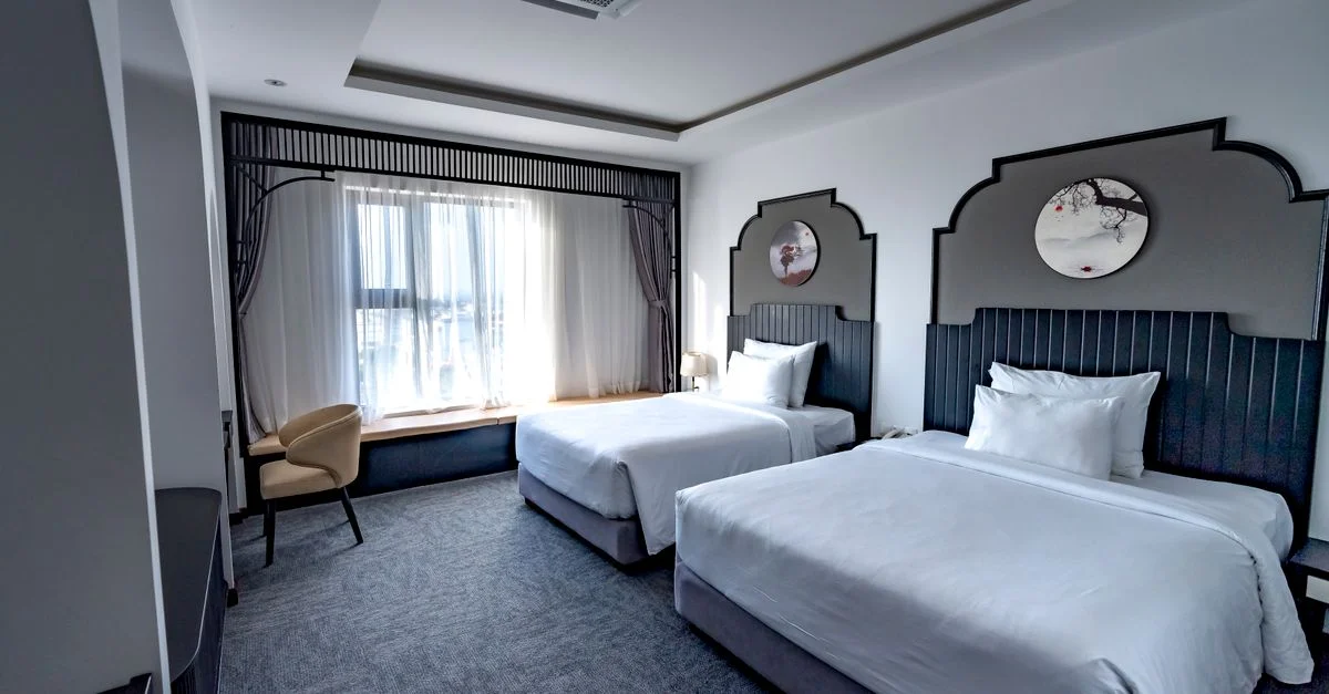 Chambre d'hôtel spacieuse avec deux lits jumeaux, décor élégant et mobilier stylé.