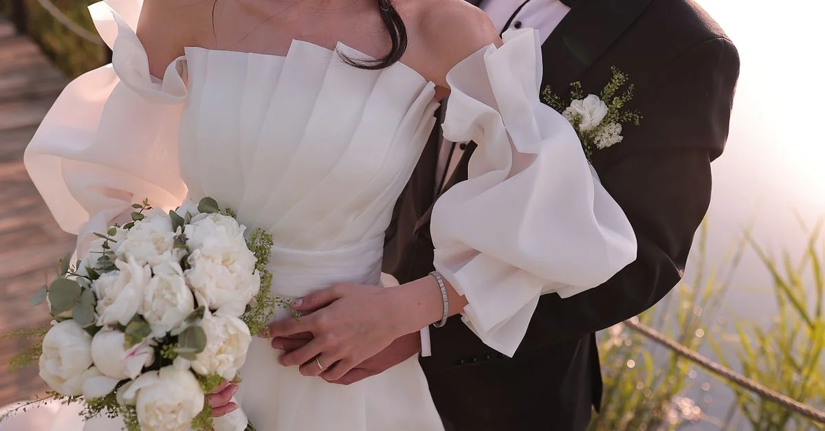 Photo de mariage romantique en extérieur d'une mariée et d'un marié s'enlaçant avec un bouquet.