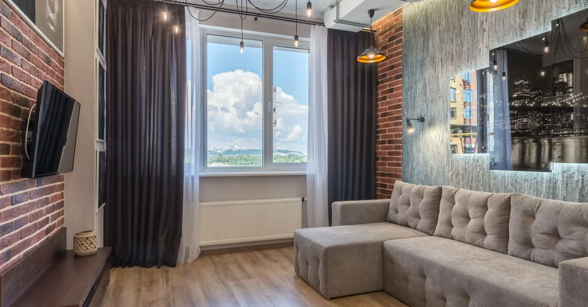 Salon contemporain avec décor urbain, grande fenêtre avec vue et meubles élégants.